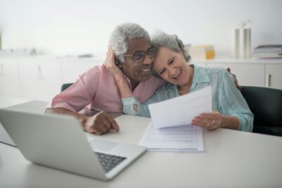 Smiling senior couple at desk with laptop looking over finances