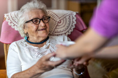 Care manager hands senior female a cup of tea