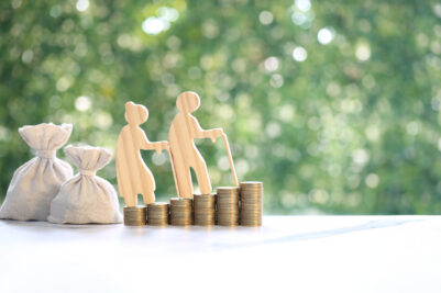 Elderly couple wooden figures walking up on a stack of coins with money bags, symbolizing retirement planning, pension, financial security and long-term savings for old age